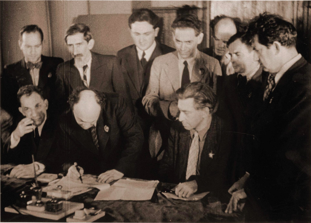 <p>Jewish cultural figures who would become members of the Jewish Anti-Fascist Committee signing an appeal to world Jewry to support the Soviet war effort against Nazi Germany, Moscow, 1941. (Front row, left to right) Dovid Bergelson, Solomon Mikhoels, and Ilya Ehrenburg; (second row) David Oistrakh, Yitskhok Nusinov, Yakov Zak, Boris Iofan, Benjamin Zuskin, Aleksandr Tyshler, Shmuel Halkin. (United States Holocaust Memorial Museum via <a href="https://yivoencyclopedia.org/article.aspx/Bergelson_Dovid">YIVO Encyclopedia</a>)</p>