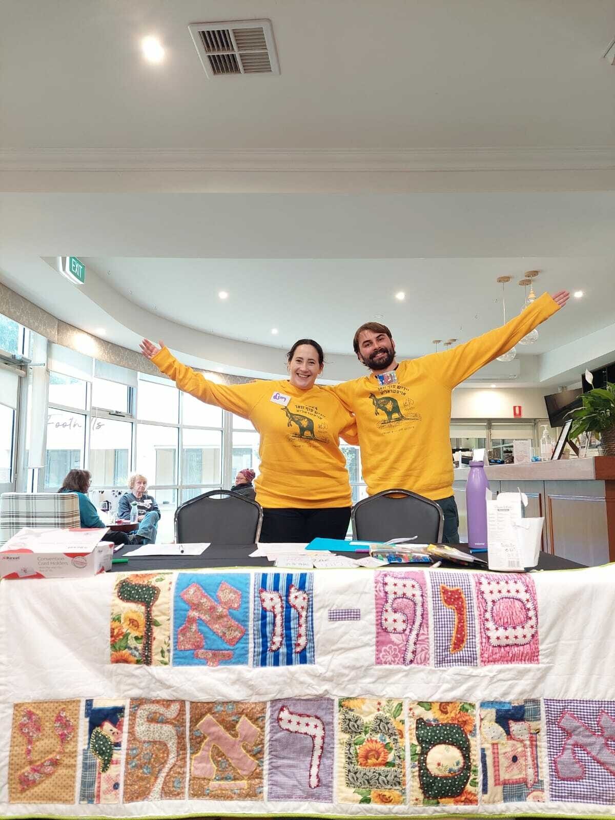 <p>Reyzl Zylberman and Daniel Goldberg, Yiddish Sof Vokh Committee members, modelling the new merch.</p>