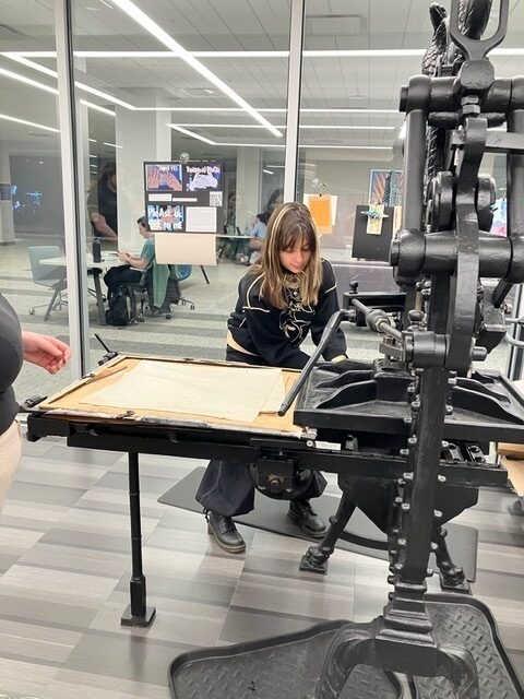 <p>A student from Dr. Rachel Kranson’s Jews and the City class prints out a headline using an 1890s-era printing press</p>