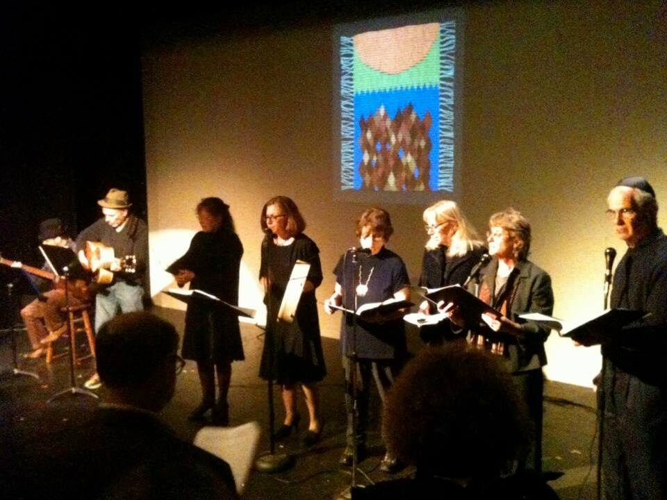 <p><em>MameLoshn</em>, Oak Park’s Yiddish singing group, commemorates Yom HaShoah. Projected behind them is an image of Berit Engen’s tapestry, <i>“Mir zainen do!” </i></p>